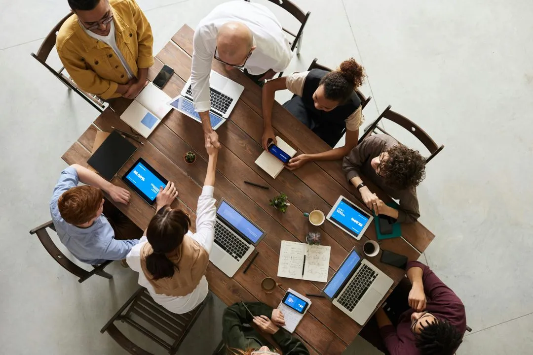 Insurance team collaborating around a table with laptops and tablets.